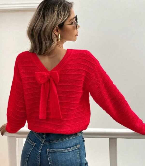 woman wearing red sweater with a ribbon and dark jeans