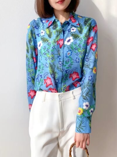 woman standing in silk colorful blouse and white jeans