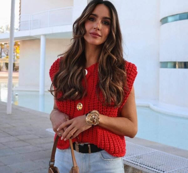 woman with brown hair wearing red sleeveless cardigan and jeans