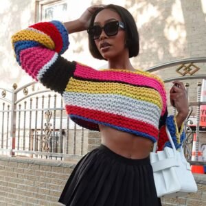 woman wearing stylish colorful sweater, black short skirt and holding a white bag, the street behind her