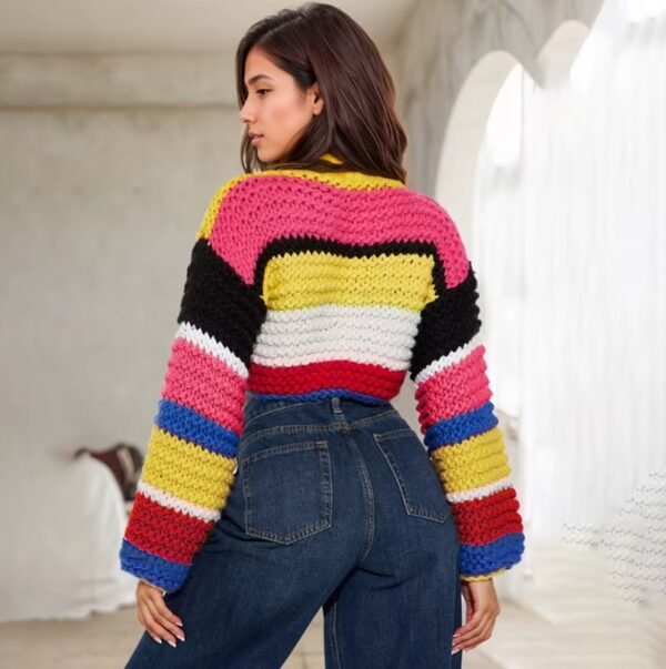 woman with short brown hair turned to her back wearing stylish colorful sweater and jeans, a white room behind her