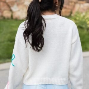 woman with black hair turned to her back wearing sweet colorful cardigan and jeans