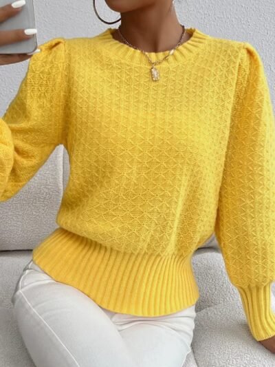 woman wearing yellow sweater and white jeans, she is holding her phone and sitting on a white sofa
