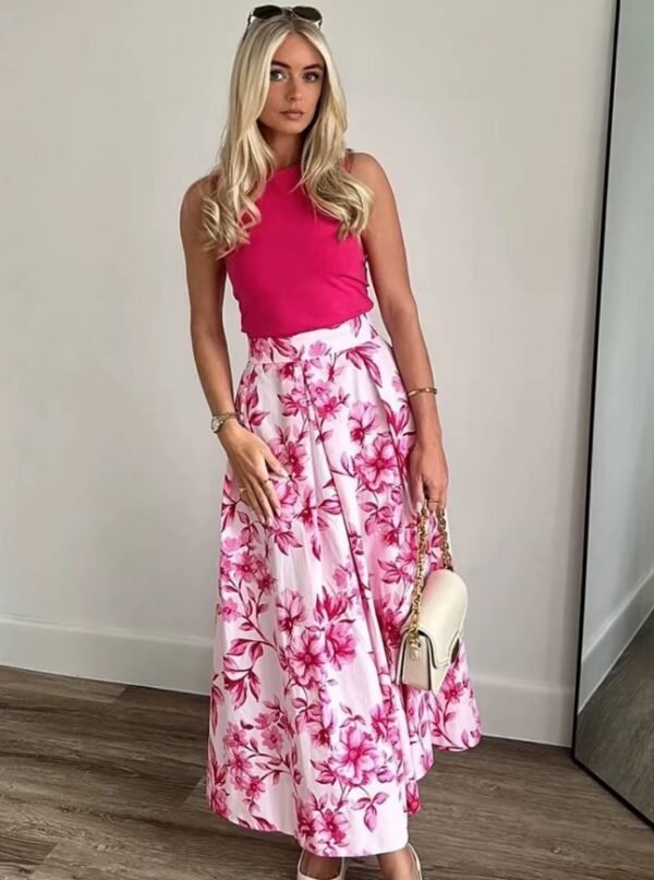 blonde woman wearing Japanese colorful skirt and a pink top, white wall behind her