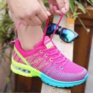 woman tying laces of athletic colorful sneakers on a wooden floor, sunglasses next to her