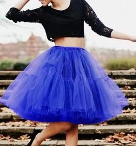 woman wearing royal blue colorful evening skirt, black top and black flats, she is dancing on the stairs