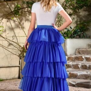 woman turned to her back wearing blue colorful multi-layer skirt and a white top