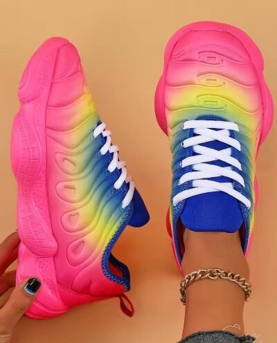 woman wearing one of colored sneakers and holding the other one, orange background