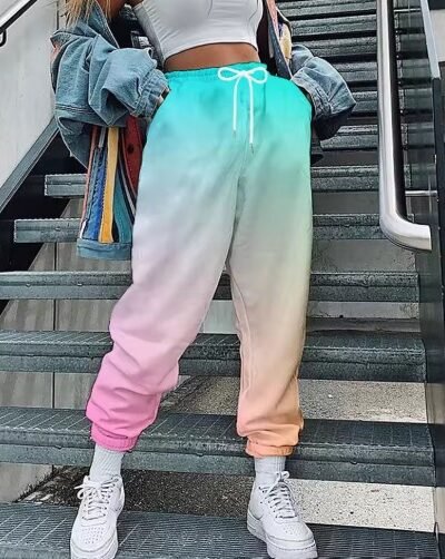 woman wearing colorful cargo pants, white top and white sneakers, grey stairs behind her