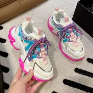 woman holding one of colorful color blocking sneakers, the other one is lying on the floor