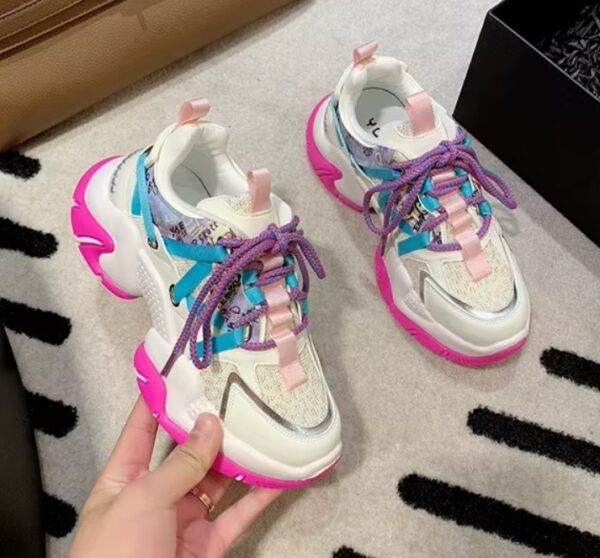 woman holding one of colorful color blocking sneakers, the other one is lying on the floor