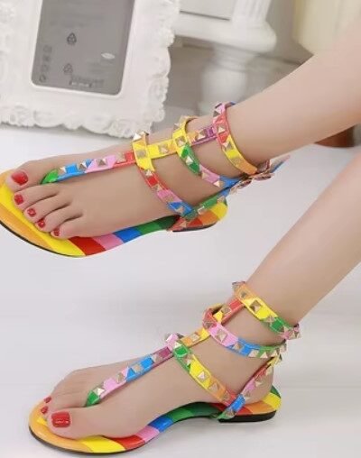 woman wearing colorful gladiator sandals, white room in the background
