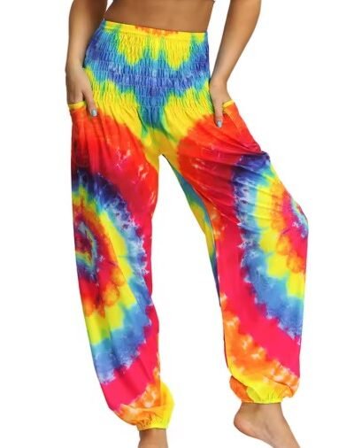 woman wearing colorful palazzo pants and lifting one foot, white backgorund