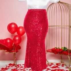 woman wearing colorful party skirt and a white button shirt, red balloons and rose petals next to her