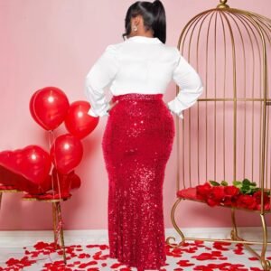 woman wearing red colorful party skirt and a white button shirt turned to her back, red balloons and rose petals next to her