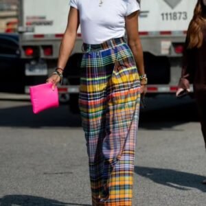 woman wearing colorful plaid pants and white T-shirt, she is holding a hot pink purse