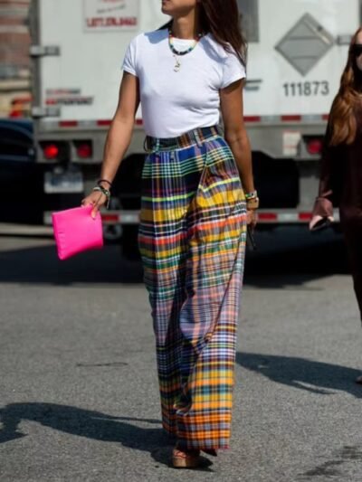 woman wearing colorful plaid pants and white T-shirt, she is holding a hot pink purse