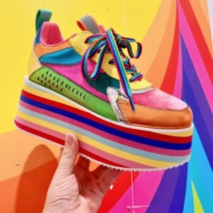 woman holding colorful platform sneakers on a bright colorful background