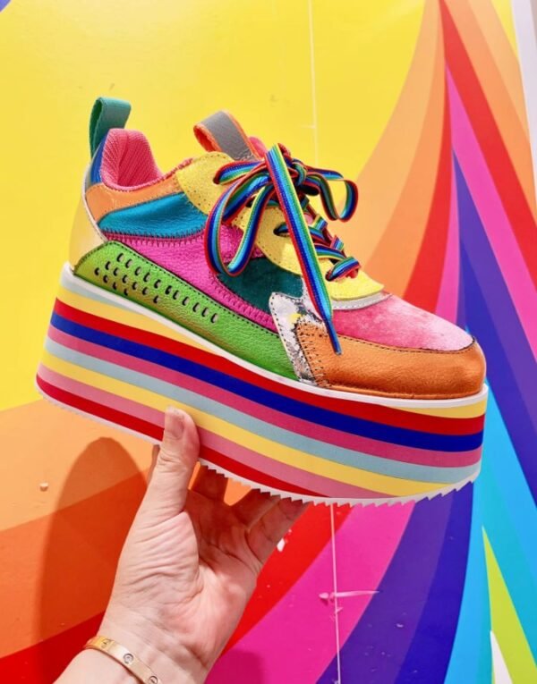 woman holding colorful platform sneakers on a bright colorful background