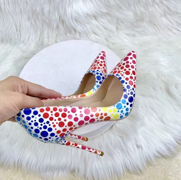 woman holding colorful polka dots heels, white fluffy carpet in the background