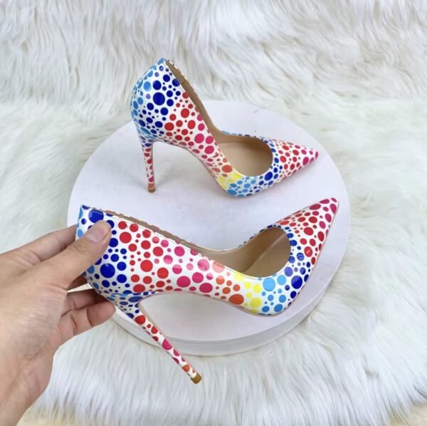 woman holding one of colorful polka dots heels, the other one is lying on a white stool