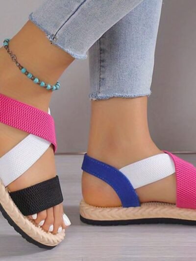 woman turned to her side wearing colorful roman sandals and bright jeans