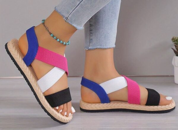 woman turned to her side wearing colorful roman sandals and bright jeans