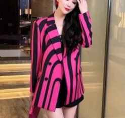 woman wearing colorful striped blazer and lifting one hand, brown room in the background