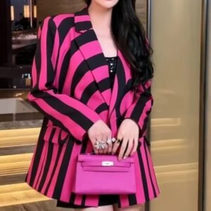 woman wearing colorful striped blazer and lifting a pink purse up