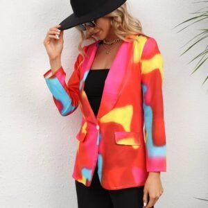 woman wearing colorful tie-dye blazer, black top, black pants and black hat, she is holding the edge of her hat