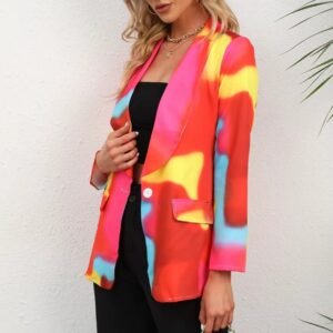 blonde woman wearing colorful tie-dye blazer and black pants, grey wall in the background