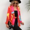 woman wearing colorful tie-dye blazer, black top, black pants and black hat, she is carrying a black purse