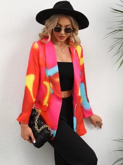 woman wearing colorful tie-dye blazer, black top, black pants and black hat, she is carrying a black purse