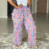 woman wearing colorful tulle pants and a white top, she is standing on a grey carpet