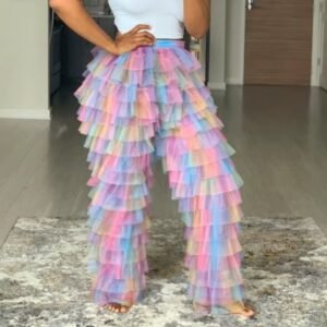 woman wearing colorful tulle pants and a white top, she is standing on a grey carpet