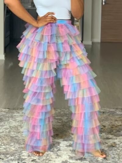 woman wearing colorful tulle pants and a white top, she is standing on a grey carpet