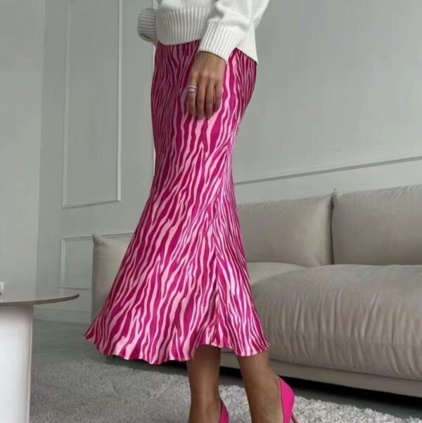 woman turned to her side wearing colorful zebra skirt and a white top, beige sofa behind her