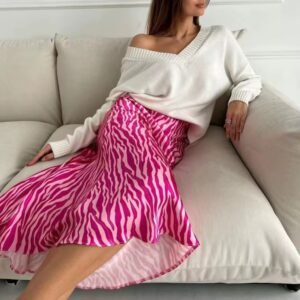 woman wearing colorful zebra skirt and a white top, she is sitting on a beige sofa