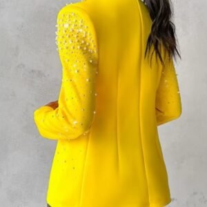 woman turned to her back wearing female yellow blazer and black pants, grey background