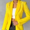 woman wearing female yellow blazer and a white top under it, she is holding the blazer's material