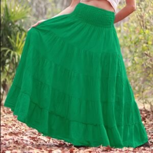 woman wearing green boho skirt and a white top, a forest in the background