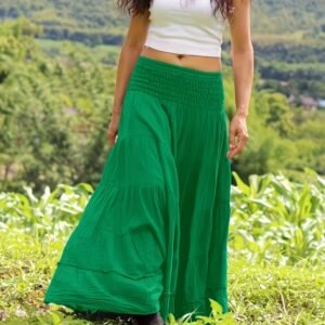 woman wearing green boho skirt and a white top, grass behind her