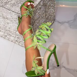 woman holding one of green high heel sandals and wearing the other one