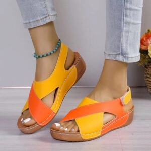 woman wearing open toe colorful sandals and jeans, grey wall in the background