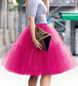 woman turned to her back wearing pink colorful evening skirt and a grey top, she id holding a black purse