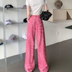 woman turned to her back wearing pink leopard print pants and white top, white room in the background