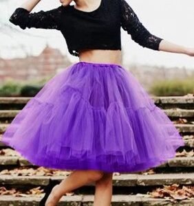 woman wearing purple colorful evening skirt, black top and black flats, she is dancing on the stairs