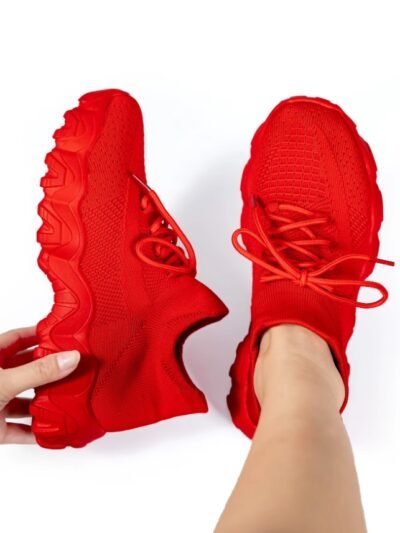woman wearing one red sneaker for women and holding the other one