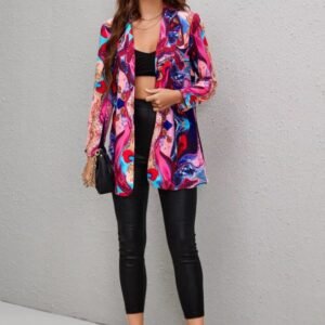 woman with brown hair wearing shiny colorful blazer, black pants and beige high heels, grey wall in the backgorund