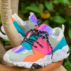 front and side view of sporty colorful sneakers, a green bush in the background